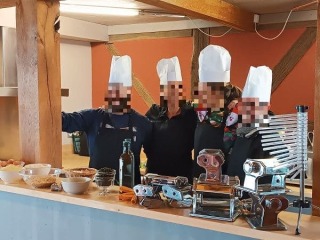 une petite équipe de collègues pose dans la cuisine où ils ont préparées des pâtes maison, une des 6 meilleures activités à réaliser au cours d'un séminaire d'entreprise en petite équipe à Family Ecolodge Puisaye