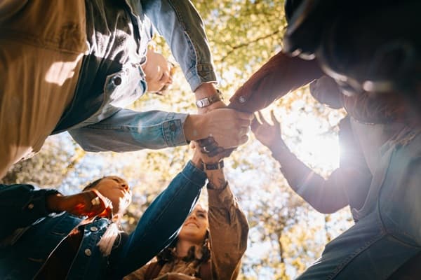 Un groupe de collaborateurs est réuni et se tape dans la main, le temps d’un séminaire porteur de sens à Family Ecolodge.